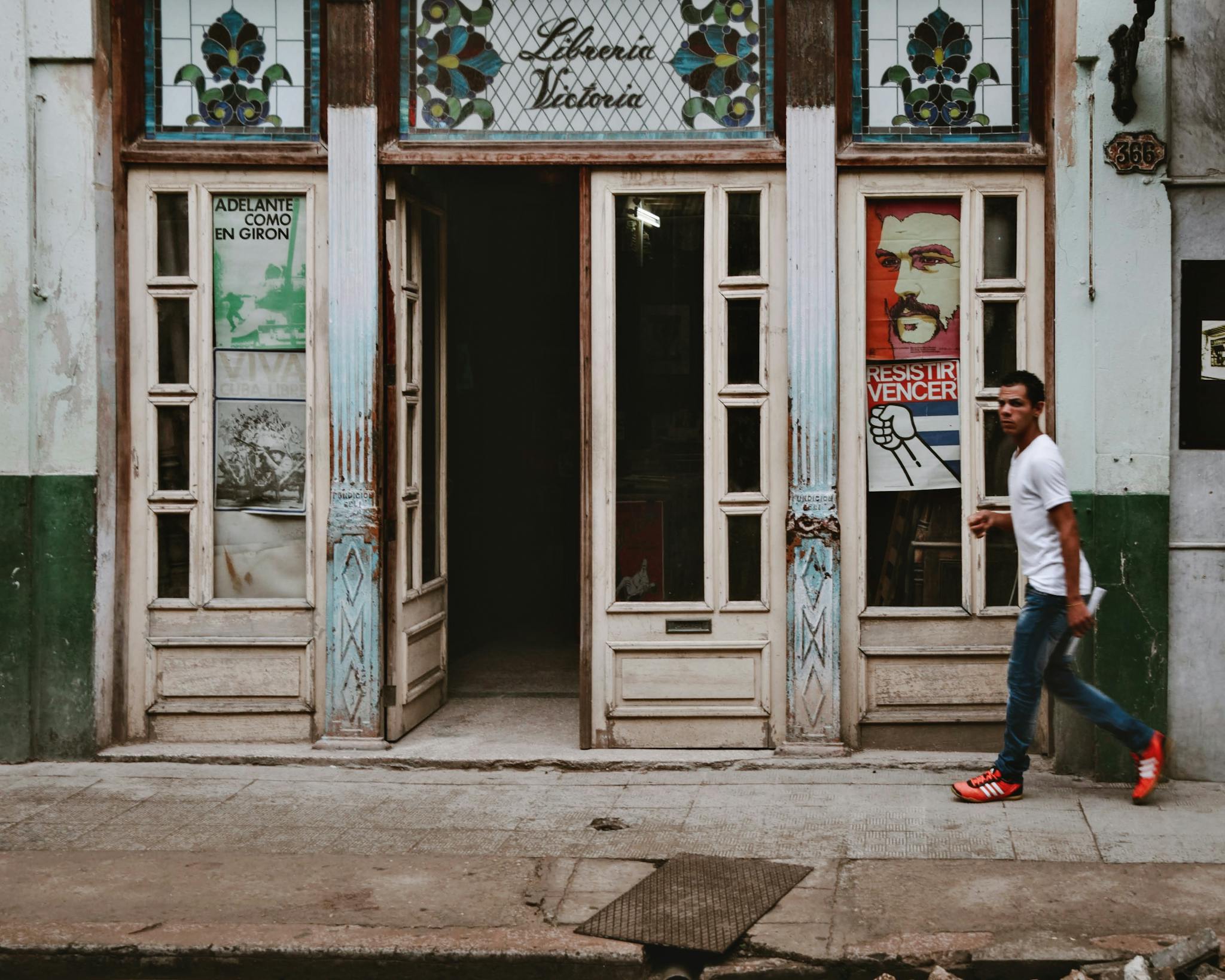 A pedestrian walks past an ornately decorated historic building entrance, capturing urban life.